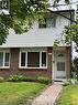 Brick and siding exterior featuring a white entry door with an arched window, white-framed windows, a paver walkway, and mature landscaping - 227 Fergus Avenue, Kitchener, ON 