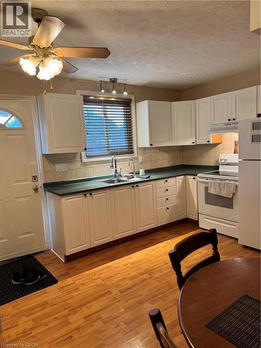 Light-toned wood-finish flooring complements the kitchen's white cabinetry and green countertops - 227 Fergus Avenue, Kitchener, ON 