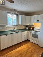 Kitchen featuring wood-finish flooring, white cabinetry, and dark countertops - 