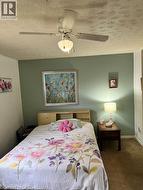 Carpeted room featuring a ceiling fan with integrated lighting, a window with blinds and drapes, and a built-in headboard with shelving - 