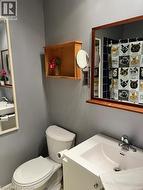 Bathroom featuring a white bathtub, blue tiled shower surround, framed wall mirror, white toilet, and a vanity with an integrated sink - 
