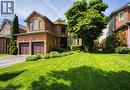 Brick exterior home featuring a two-car garage, arched windows, and a landscaped front yard with mature trees - 5 Shetland Drive, Waterdown, ON 