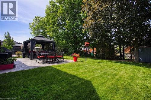 Expansive backyard featuring a concrete patio, mature trees, and a storage shed - 5 Shetland Drive, Waterdown, ON 