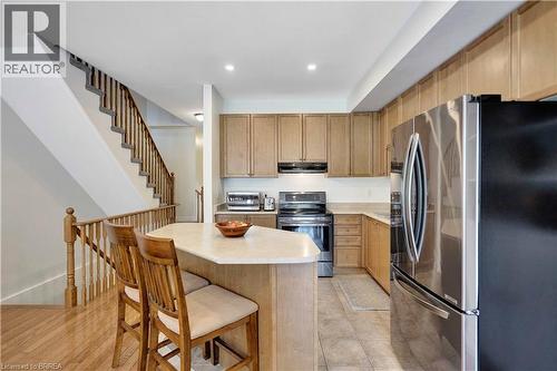 Kitchen featuring wood-finish cabinetry, stainless steel appliances, and an eat-in island with seating - 120 Beddoe Drive Unit# 6, Hamilton, ON 