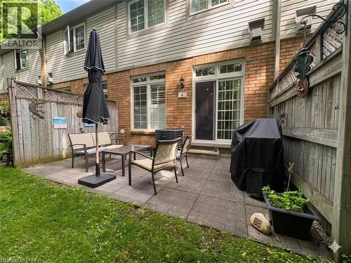Paved patio area featuring a sliding glass door, a brick exterior, and a privacy fence - 120 Beddoe Drive Unit# 6, Hamilton, ON 