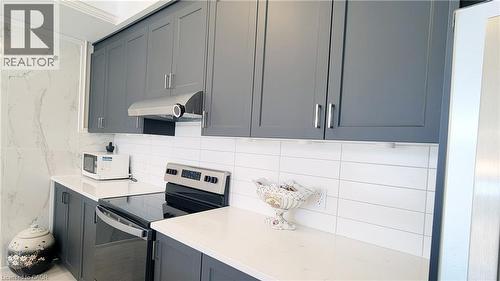 Contemporary kitchen featuring shaker-style cabinetry, a stainless steel range hood, white subway tile backsplash, and light-toned countertops - 142 Foamflower Place Unit# 12, Waterloo, ON - Indoor Photo Showing Kitchen With Upgraded Kitchen