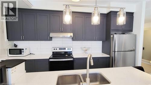 Modern kitchen featuring dark grey shaker-style cabinetry, white subway tile backsplash, and stainless steel appliances - 142 Foamflower Place Unit# 12, Waterloo, ON - Indoor Photo Showing Kitchen With Double Sink With Upgraded Kitchen