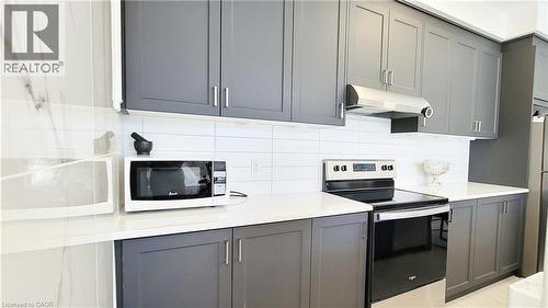 Kitchen featuring sleek gray cabinetry, white countertops, a white subway tile backsplash, and stainless steel appliances including a range and range hood - 142 Foamflower Place Unit# 12, Waterloo, ON - Indoor Photo Showing Kitchen With Upgraded Kitchen
