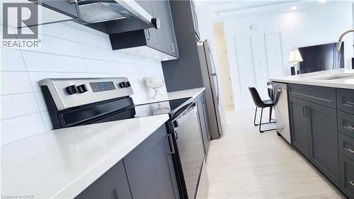 Modern kitchen featuring dark grey cabinetry, light countertops, stainless steel appliances, and a white subway tile backsplash - 142 Foamflower Place Unit# 12, Waterloo, ON - Indoor Photo Showing Kitchen