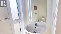 Pedestal sink with chrome faucet, wall-mounted mirror, and frosted window - 