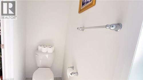 Compact water closet featuring a white ceramic toilet, light-toned tile flooring, and chrome fixtures - 142 Foamflower Place Unit# 12, Waterloo, ON - Indoor