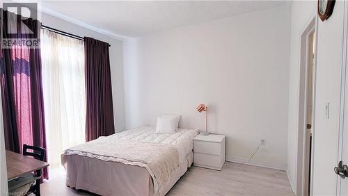 Room featuring light wood-finish flooring, white walls, and a window with sheer and blackout curtains - 142 Foamflower Place Unit# 12, Waterloo, ON - Indoor Photo Showing Bedroom