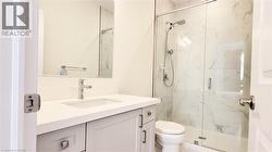 Bathroom featuring a frameless glass shower enclosure with white marble-style subway tile surround, a built-in shower niche, and a shower head with handheld sprayer - 