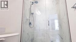 Walk-in shower featuring glass enclosure, white marble-look tile surround, dual shower heads, and chrome fixtures - 