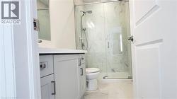 Modern bathroom featuring a white floating vanity with a light countertop, a glass-enclosed shower with white tiled walls, and coordinating floor tiling - 
