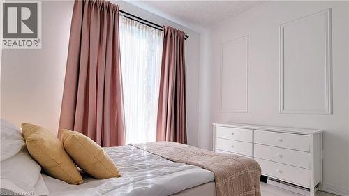Bright room featuring a window with sheer and blackout curtains, a white six-drawer dresser, and decorative wall molding - 142 Foamflower Place Unit# 12, Waterloo, ON - Indoor Photo Showing Bedroom