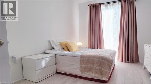 Room featuring light wood-finish flooring, white painted walls, and a window dressed with sheer and solid curtains - 142 Foamflower Place Unit# 12, Waterloo, ON - Indoor Photo Showing Bedroom