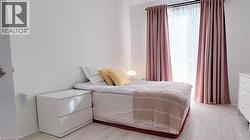 Room featuring light wood-finish flooring, white painted walls, and a window dressed with sheer and solid curtains - 