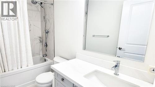 Bathroom featuring a white bathtub with a tile surround, a built-in toilet, a single vanity with a white countertop, an undermount sink, and a chrome faucet - 142 Foamflower Place Unit# 12, Waterloo, ON - Indoor Photo Showing Bathroom
