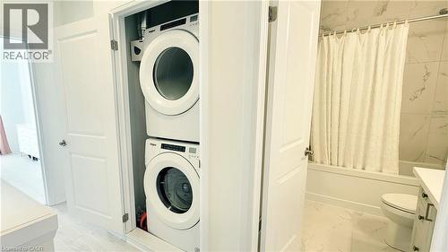 Integrated laundry closet featuring a stacked white washer and dryer unit - 142 Foamflower Place Unit# 12, Waterloo, ON - Indoor Photo Showing Laundry Room