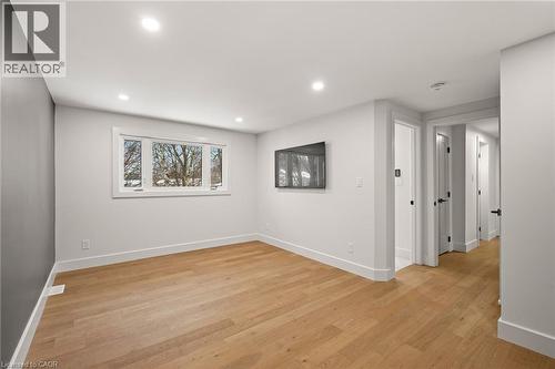 Spacious room featuring wood-finish flooring, recessed lighting, a large window, and multiple interior doorways with matte black hardware - 361 Coleridge Place, Waterloo, ON - Indoor Photo Showing Other Room