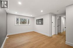 Spacious room featuring wood-finish flooring, recessed lighting, a large window, and multiple interior doorways with matte black hardware - 