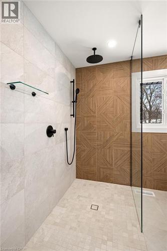 Walk-in shower featuring a rain showerhead, hand sprayer, wood-finish accent wall, large format tile, and mosaic tile flooring - 361 Coleridge Place, Waterloo, ON - Indoor Photo Showing Bathroom