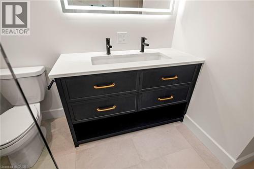 Bathroom vanity featuring a quartz countertop with an integrated sink, matte black faucets, and an illuminated mirror - 361 Coleridge Place, Waterloo, ON - Indoor