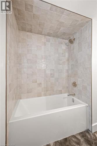 Bathtub and shower combination featuring neutral square wall tiles, a white porcelain tub, and brushed nickel fixtures - 361 Coleridge Place, Waterloo, ON - Indoor Photo Showing Bathroom