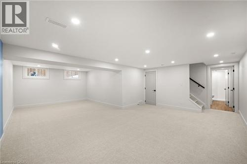 Spacious finished lower level featuring recessed lighting, light-toned carpeting, egress windows, and a staircase with a black handrail - 361 Coleridge Place, Waterloo, ON - Indoor Photo Showing Basement