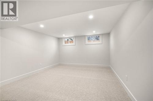 Spacious room featuring light-toned carpeting, neutral wall paint, recessed ceiling lighting, and two egress windows - 361 Coleridge Place, Waterloo, ON - Indoor Photo Showing Other Room
