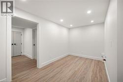Bright room featuring wood-finish flooring, recessed lighting, and crisp white walls - 
