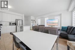 Open-concept living space with a contemporary kitchen featuring white cabinetry and stainless steel appliances - 