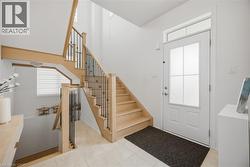 Entryway featuring a light wood-finish staircase with black iron spindles, a white paneled door with frosted glass inserts, and a transom window - 