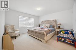 Spacious bedroom featuring light-colored carpet flooring, a single window with horizontal blinds, and a flush-mount ceiling light fixture - 