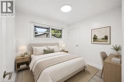 Bright bedroom featuring light wood-finish flooring, white walls, and a contemporary flush-mount ceiling light - 