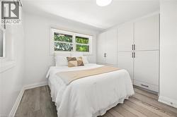 Bright bedroom featuring wood-finish flooring, white walls, and a prominent built-in storage system with matte black hardware - 