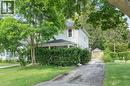 White siding residence with a covered porch, set on a property featuring mature trees and a detached garage - 35 Basil Avenue, Simcoe, ON 