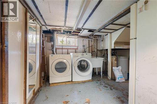 Basement utility area featuring a washer and dryer, a utility sink, and exposed ceiling joists - 35 Basil Avenue, Simcoe, ON 
