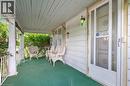Covered front porch featuring white siding and a green outdoor carpet - 35 Basil Avenue, Simcoe, ON 