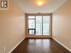 Expansive window wall with horizontal blinds, showcasing wood-finish flooring, light-colored walls, and a ceiling-mounted light fixture - 