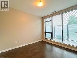 Expansive windows with horizontal blinds, dark wood-finish flooring, light neutral-toned walls, white baseboards, and a flush-mount ceiling light fixture - 