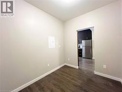 Interior room featuring wood-finish flooring, light-toned walls, and white baseboards - 