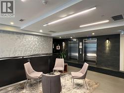 Lobby area featuring two stainless steel elevators, overhead linear lighting, recessed ceiling lights, and wall-mounted sconces - 