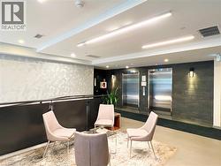 Lobby area featuring dual stainless steel elevators, patterned accent wall, recessed and linear ceiling lighting, and dark textured wall finishes - 