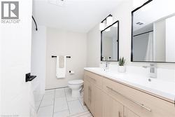 Bathroom featuring a double vanity with light wood-finish cabinetry, white countertops, and chrome faucets - 
