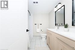Modern bathroom featuring a double vanity with light wood-finish cabinetry, white countertops, and contemporary black-framed mirrors - 