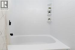 White tub-shower combination featuring subway-style wall tiling and matte black fixtures - 