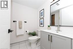 Powder room with a gray vanity featuring brushed nickel hardware, a white integrated sink, and a rectangular mirror with a black frame - 