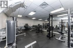 Fitness center featuring black rubber flooring, mirrored walls, recessed lighting, and a drop ceiling - 